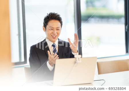 A man in a suit making a video call to a PC 69328804
