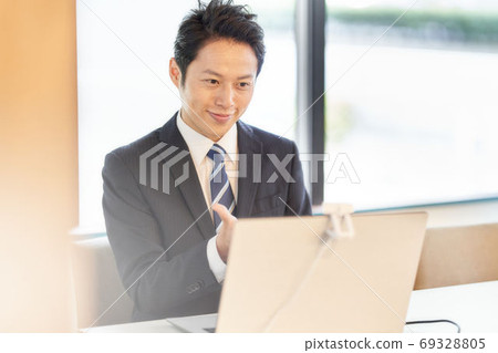 A man in a suit making a video call to a PC A man in a suit making a video call to a PC 69328805