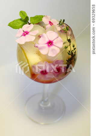 Chilled fruit tea with ice cubes and garnished with a sprig of mint 69329658