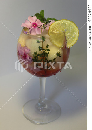 In a clear glass of lemon juice with ice cubes and decorated with flowers close up In a clear glass of lemon juice with ice cubes and decorated with flowers close up 69329665