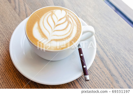Close-up of hot cappuccino coffee dressing with leave shape of latte art Close-up of hot cappuccino coffee dressing with leave shape of latte art 69331197