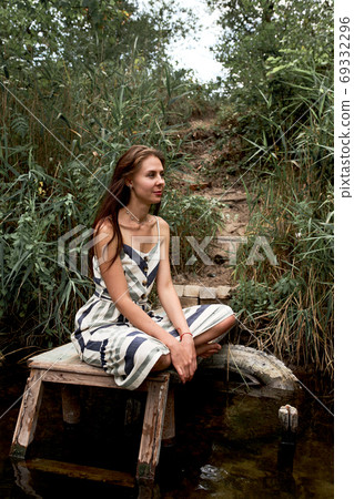 Beautiful young caucasian woman in dress having rest on the nature. 69332296