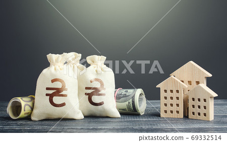 Ukrainian hryvnia money bags and residential buildings figures. Investments in real estate. Municipal budget management. Mortgage loan. Financing the construction and renovation of housing. Taxes. 69332514
