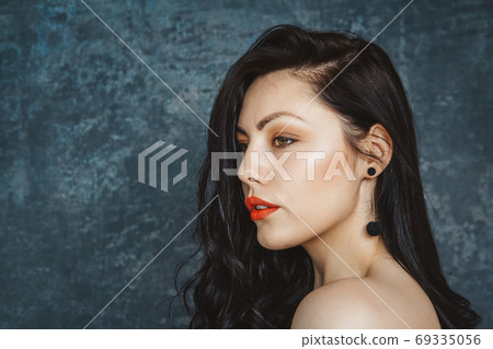 Fashionable portrait beautiful woman of a stylish brunette with red lips. Woman with long hair wearing black earrings. Set on gray background Fashionable portrait beautiful woman of a stylish brunette with red lips. Woman with long hair wearing black earrings. Set on gray background 69335056