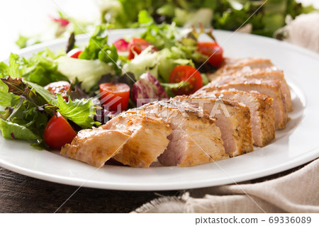 Grilled chicken breast with vegetables on a plate on wooden table. 	 69336089