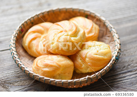 Cream puffs filled vanilla custard on basket wooden background - 69336580