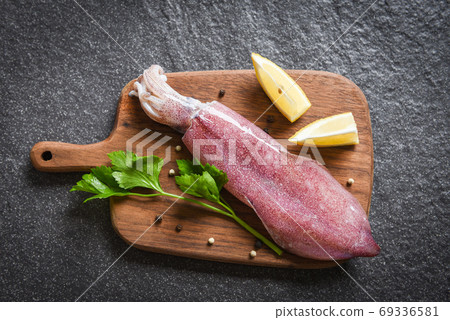 Raw squid on wooden cutting board with lemon parsley on the dark 69336581