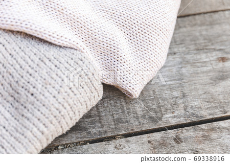 Autumn or winter background. Stack of cozy knitted wool clothes sweaters on wooden table. Hygge mood, cold weather concept. Handmade knitted sweaters. 69338916