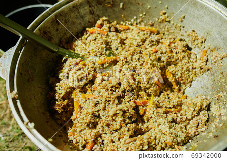 Cooking of tasty pilau with meat in a large boiler outside. Street food. Close-up. 69342000