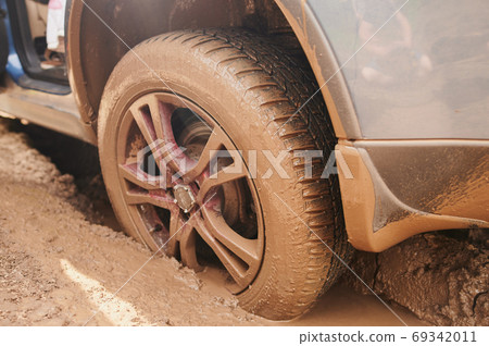 Wheel closeup in a countryside landscape with a muddy road. 69342011