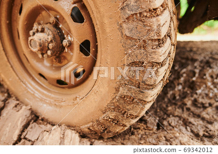 Wheel closeup in a countryside landscape with a muddy road. 69342012