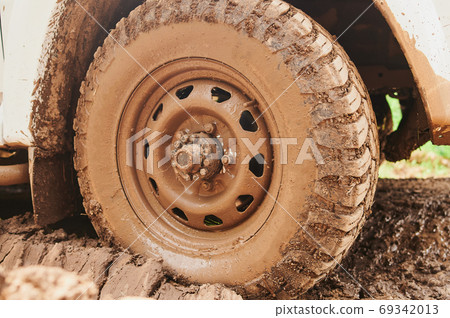 Wheel closeup in a countryside landscape with a muddy road. 69342013