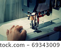 A woman sews on an industrial flat-seam sewing machine. Soft focus 69343009