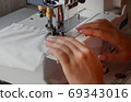 A woman sews on an industrial flat-seam sewing machine. Soft focus 69343016