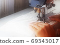 A woman sews on an industrial flat-seam sewing machine. Soft focus 69343017