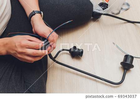 Chandelier with wires and tools on the floor, preparation to installation. Chandelier with wires and tools on the floor, preparation to installation. 69343037