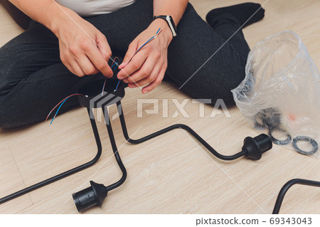 Chandelier with wires and tools on the floor, preparation to installation. Chandelier with wires and tools on the floor, preparation to installation. 69343043