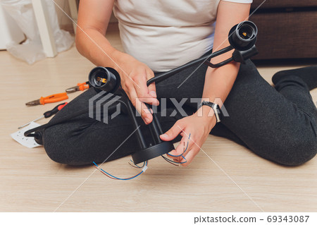 Chandelier with wires and tools on the floor, preparation to installation. Chandelier with wires and tools on the floor, preparation to installation. 69343087