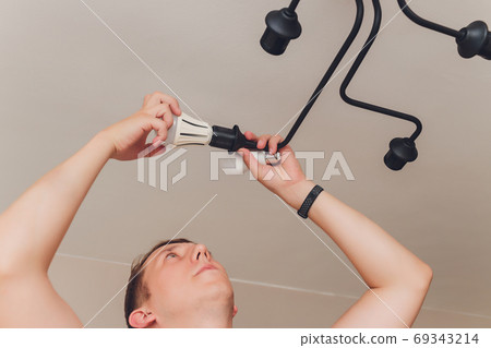 an electrician. repair work. Chandelier to hang on the ceiling. an electrician. repair work. Chandelier to hang on the ceiling. 69343214
