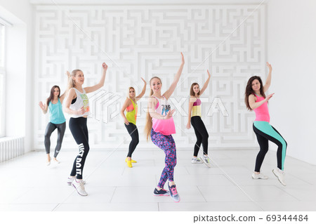 Group of young women in sportswear at Zumba dance fitness class Group of young women in sportswear at Zumba dance fitness class 69344484