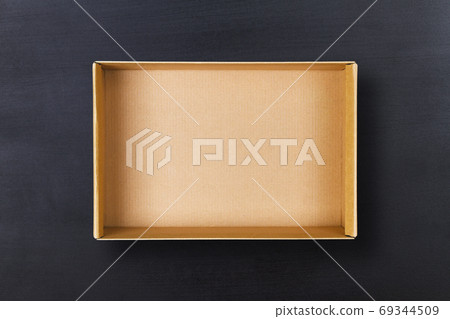 Open cardboard box on chalkboard background. Empty cardboard package on black texture 69344509