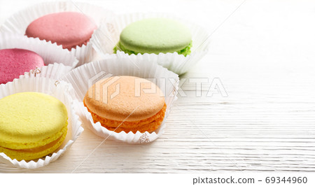 Colorful macarons cakes in paper baskets on white wooden background. Copy space Colorful macarons cakes in paper baskets on white wooden background. Copy space 69344960