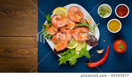 Prawns Shrimps cooked with garlic and rosemary, served on plate on wooden table. Prawns Shrimps cooked with garlic and rosemary, served on plate on wooden table. 69345977