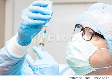 The portrait of doctor takes the medication from a bottle to an injection.  69346416