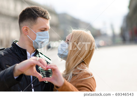 Young couple in love in protective medical mask on face outdoor at street. 69346543