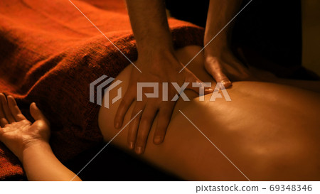Masseur doing back massage for female client in spa center Masseur doing back massage for female client in spa center 69348346
