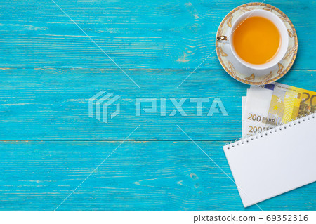 empty notepad with white pencil and 200 euro banknotes on turquoise wooden table, copy space 69352316