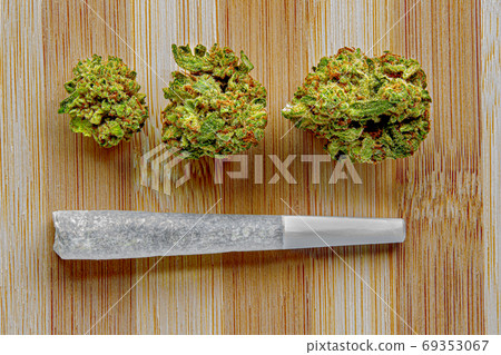 Legal Canadian Pre-Rolls Cannabis Joints on a wooden surface with cannabis dried flower. Legal Canadian Pre-Rolls Cannabis Joints on a wooden surface with cannabis dried flower. 69353067