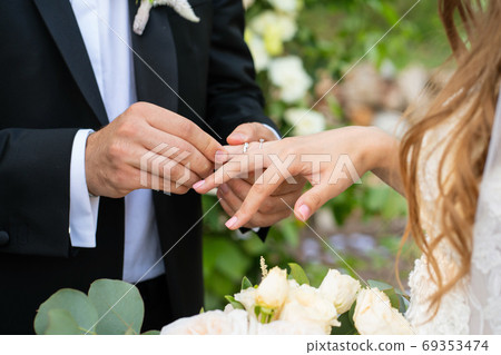 the bride and groom put on each other rings.  69353474