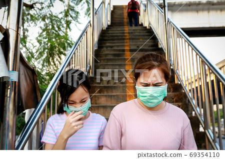 Stressed asian child girl wearing hygienic mask while walking outdoor,allergy to dust,pollution,dirty air,PM 2.5,health care,virus protection,respiratory disease,air contamination,inhaling toxic air Stressed asian child girl wearing hygienic mask while walking outdoor,allergy to dust,pollution,dirty air,PM 2.5,health care,virus protection,respiratory disease,air contamination,inhaling toxic air 69354110