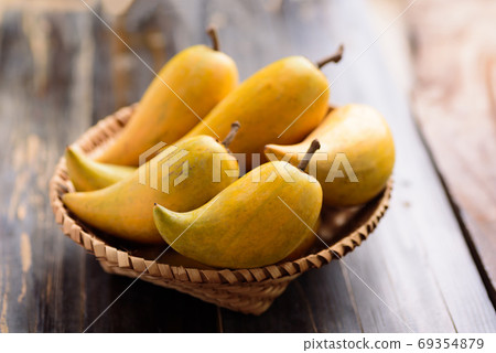 Eggfruit or canistel in a basket on wooden table 69354879