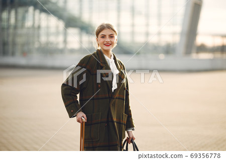 Woman with suitcase standing by the airport Woman with suitcase standing by the airport 69356778