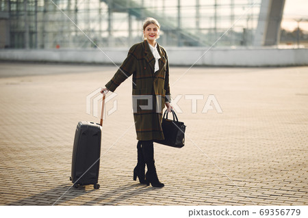 Woman with suitcase standing by the airport 69356779