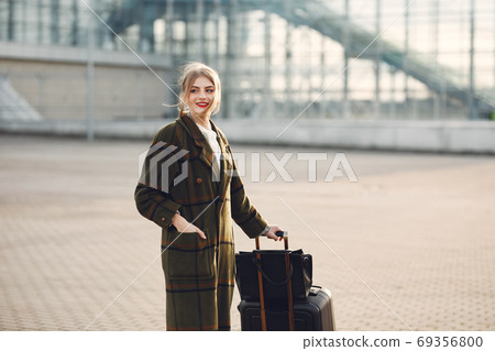 Woman with suitcase standing by the airport Woman with suitcase standing by the airport 69356800