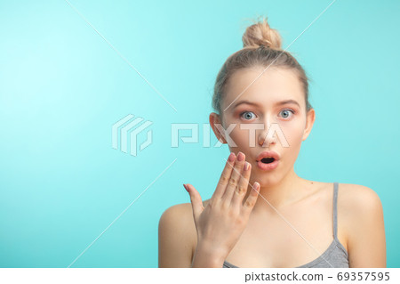 young attractive woman with hair knot staring at camera with shoked expression 69357595