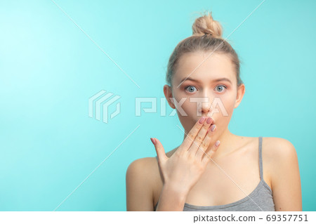 young attractive woman with hair knot staring at camera with shoked expression 69357751