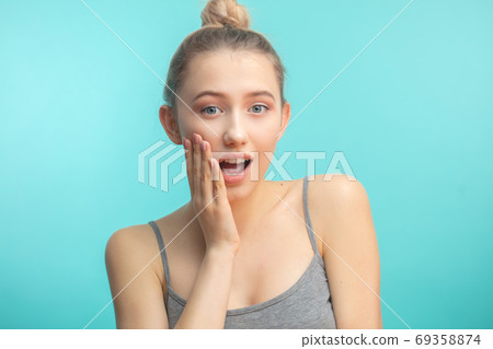 young attractive woman with hair knot staring at camera with shoked expression 69358874