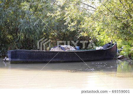 An old wooden motorboat loaded with empty fishnets left by poacherson the river 69359001