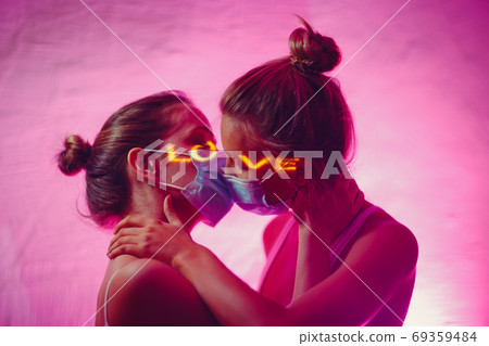 Portrait of two kissing couple young women in medical face mask Portrait of two kissing couple young women in medical face mask 69359484