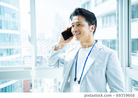Male office worker calling on a smartphone Male office worker calling on a smartphone 69359608