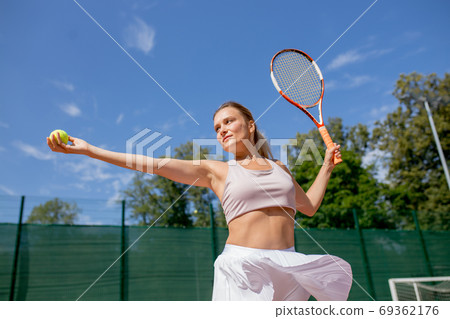 Beautiful female tennis player serving outdoor 69362176