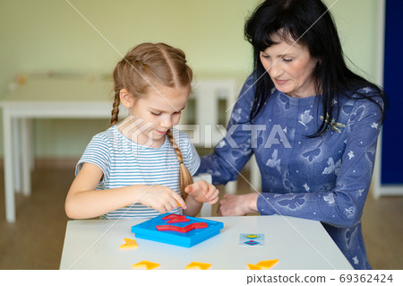 a teacher and girl solve mathematical puzzle. 69362424