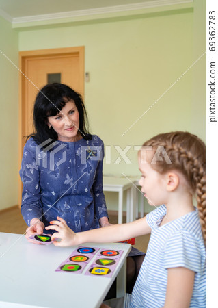 a teacher with child play cards geometric shapes. a teacher with child play cards geometric shapes. 69362783