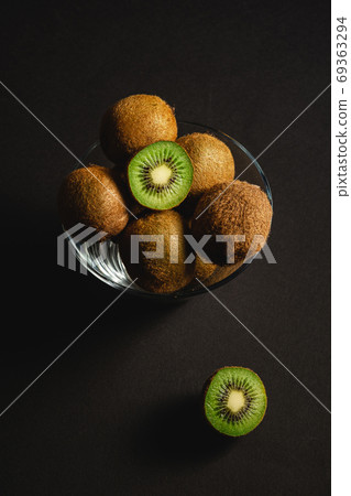Kiwi fruits half sliced in glass bowl on dark background 69363294