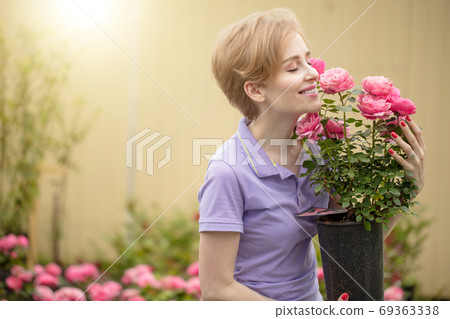 Beautiful young woman with roses posing in garden Beautiful young woman with roses posing in garden 69363338