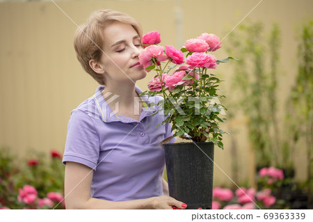 Beautiful young woman with roses posing in garden Beautiful young woman with roses posing in garden 69363339